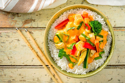 Assiette de légumes et tofu dans une sauce au coco et cari sur un lit de riz basmati.